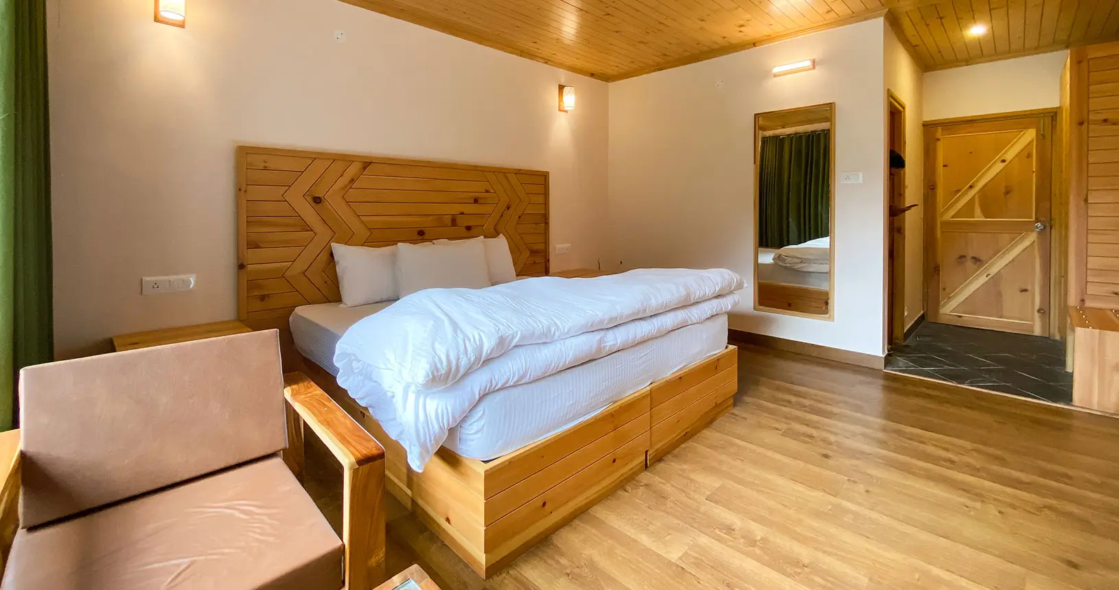 Bed and entrance of deluxe room in Hotel Batseri, Sangla.